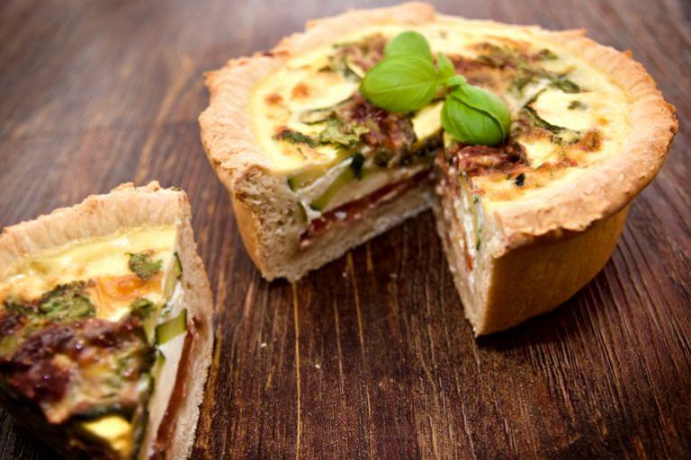 A delicious deep layered Mediterranean quiche with basil garnish.